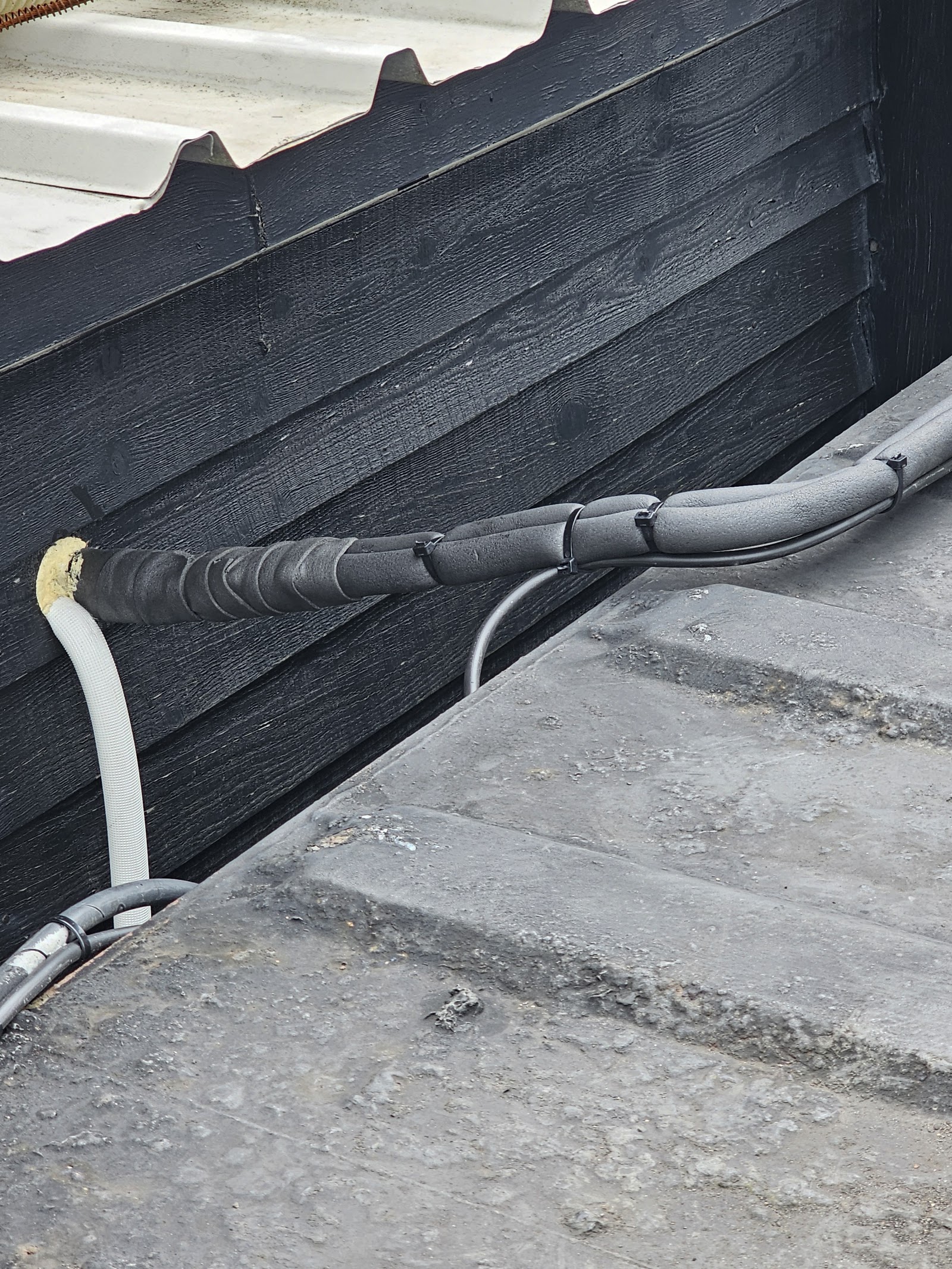 External cable run and containment feeding a rooftop plant supply, weatherproofed and dressed in.