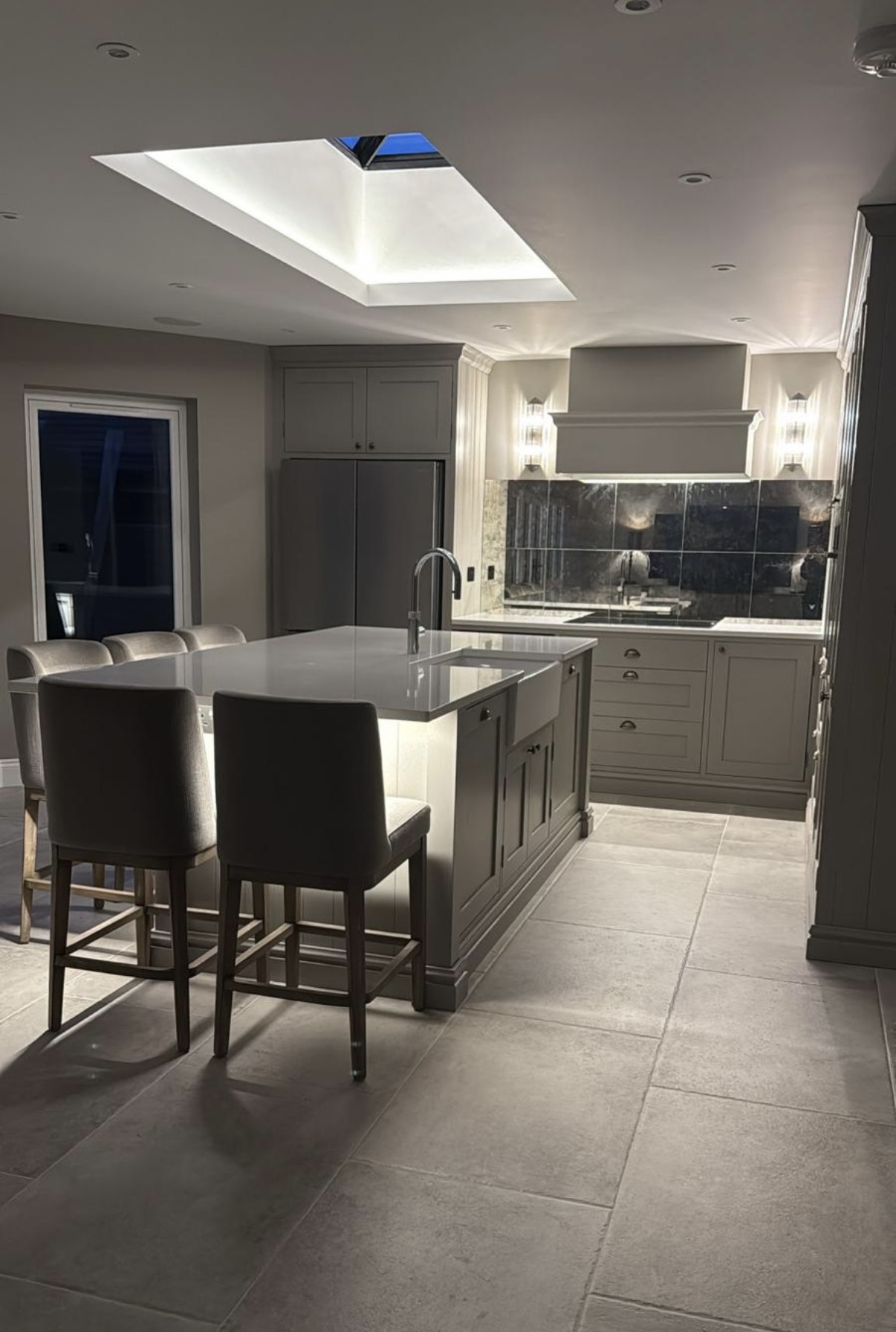 Evening lighting in a finished kitchen — layered downlights and wall lights on a completed installation.